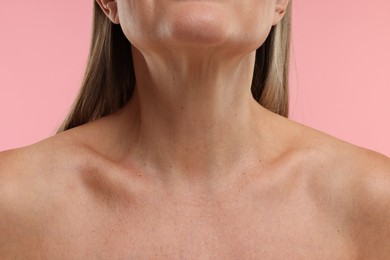 Photo of Mature woman showing her neck on pink background, closeup