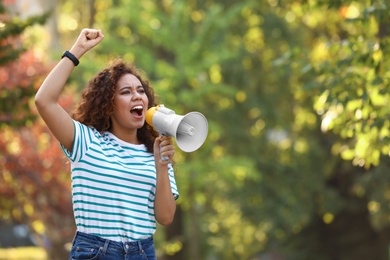 Photo of Angry African-American woman with megaphone outdoors. Protest leader