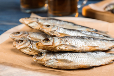 Photo of Tasty dried fish on wooden board, closeup