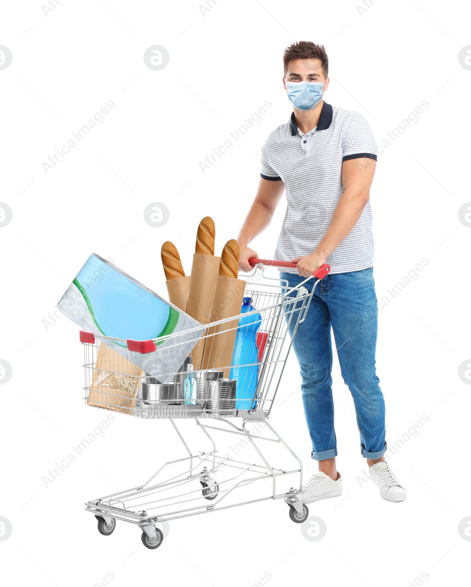 Image of Young man in medical mask and shopping cart with purchases on white background. Coronavirus pandemic  