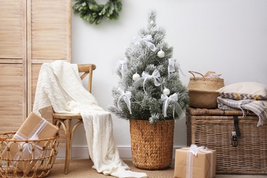 Stylish room interior with beautiful Christmas tree near white wall