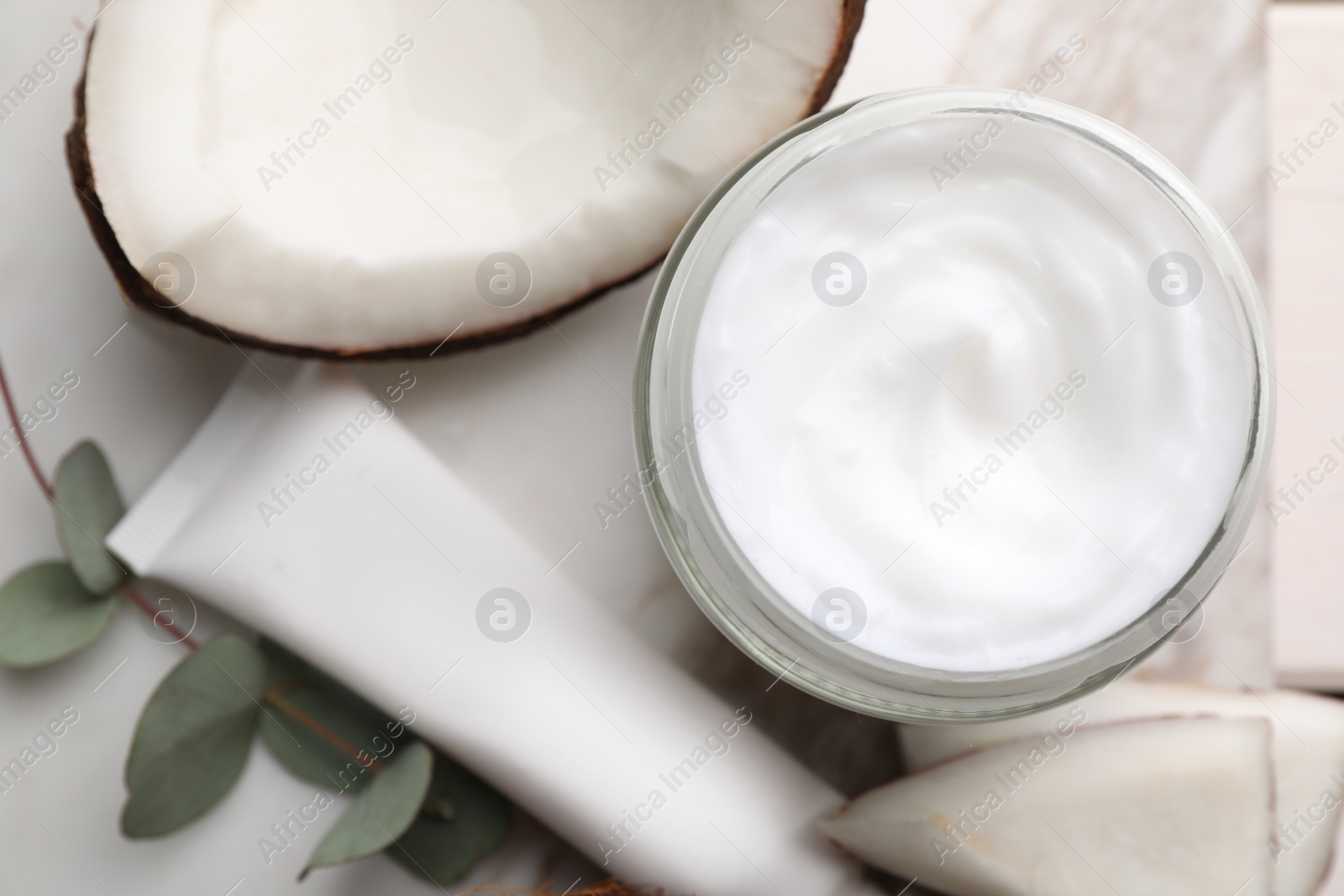 Photo of Different hand care cosmetic products, coconut pieces and eucalyptus branch on table, flat lay