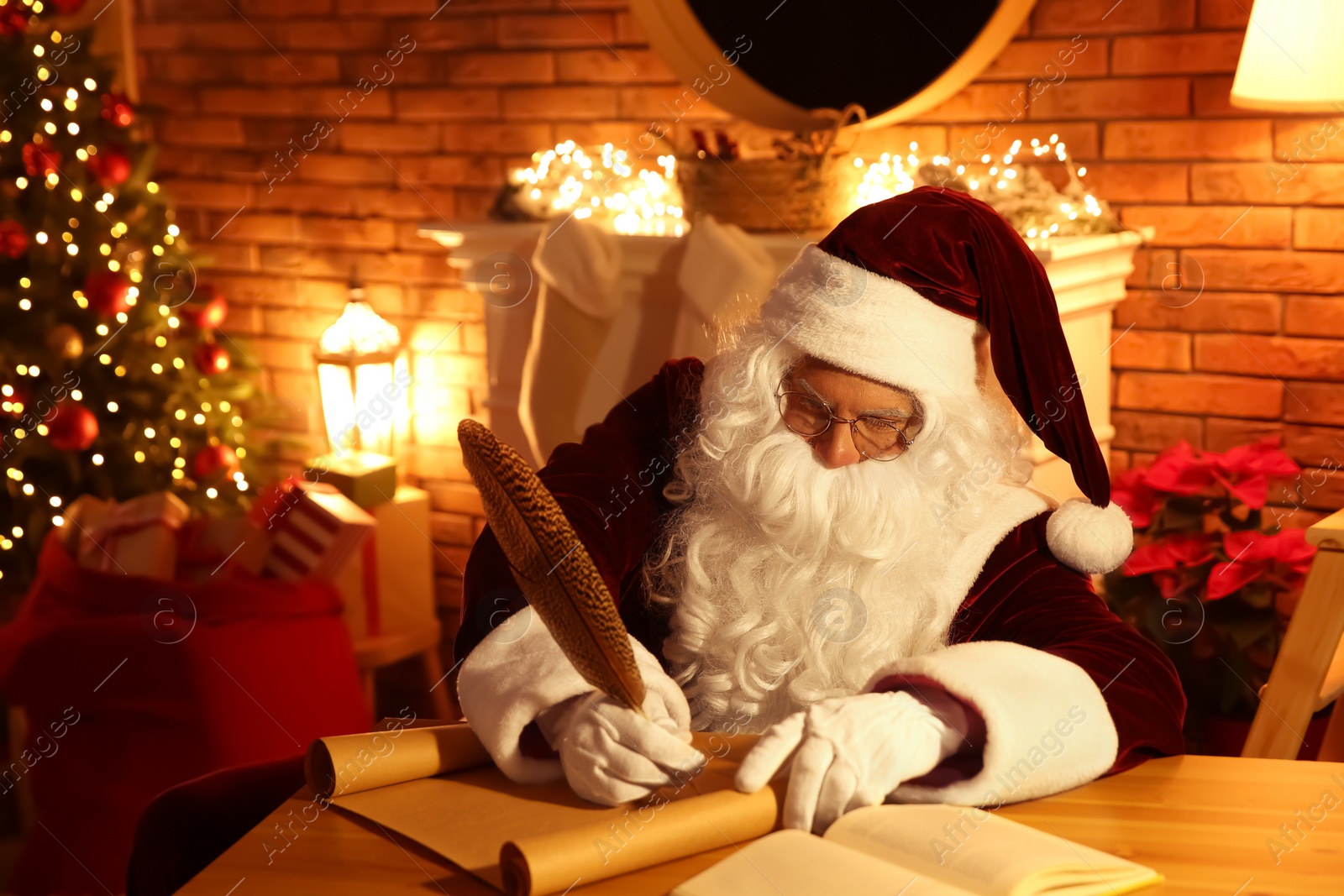 Photo of Santa Claus writing letter at table indoors