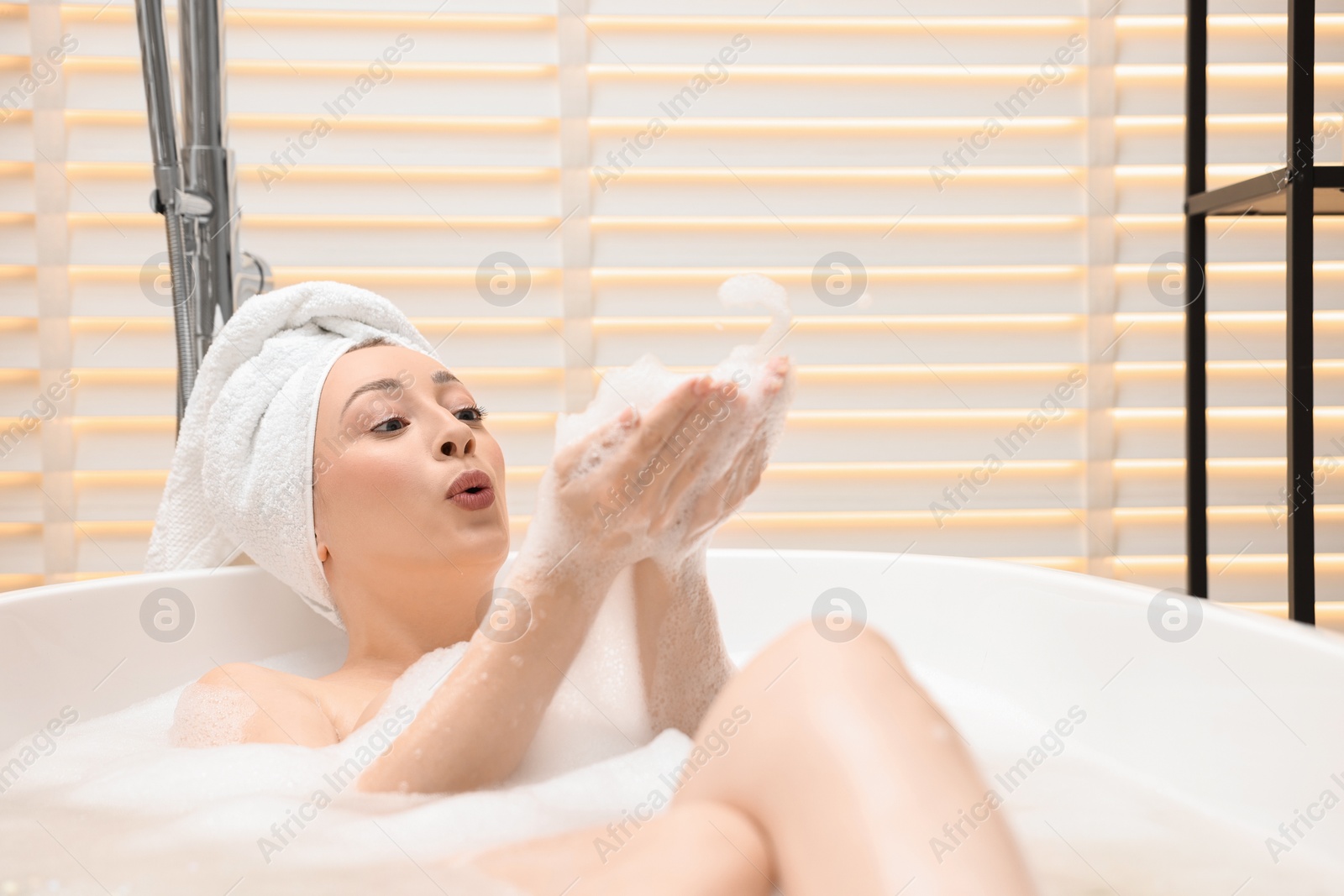 Photo of Beautiful woman taking bath with foam in tub indoors, space for text