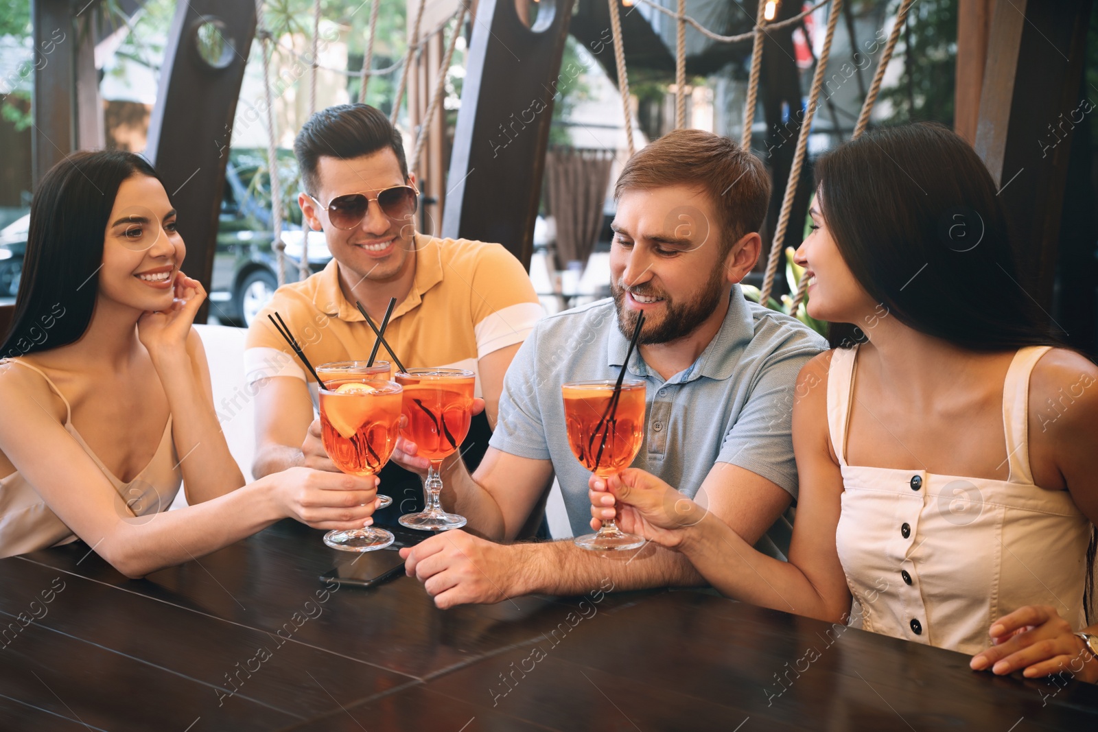 Photo of Friends with Aperol spritz cocktails resting together at restaurant