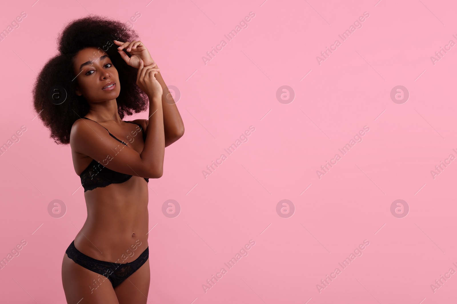 Photo of Beautiful woman in elegant black underwear on pink background, space for text