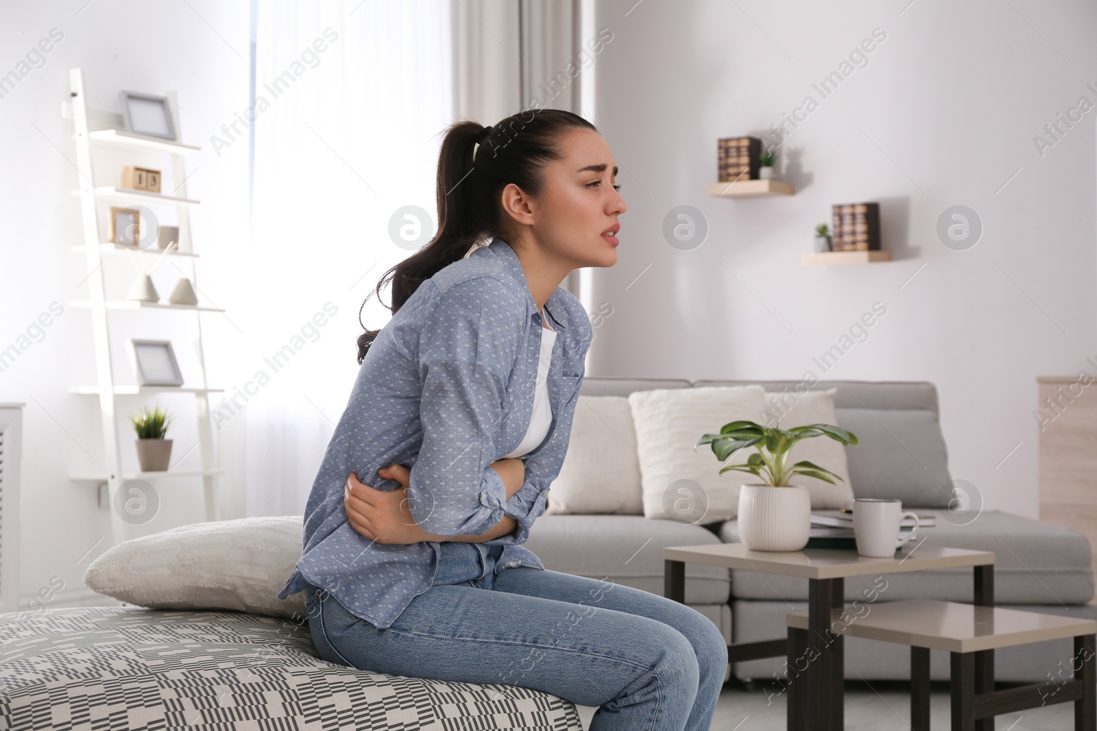 Photo of Young woman suffering from stomach ache at home. Food poisoning