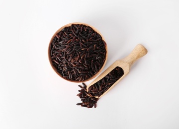 Photo of Bowl and scoop with uncooked black rice on white background, top view