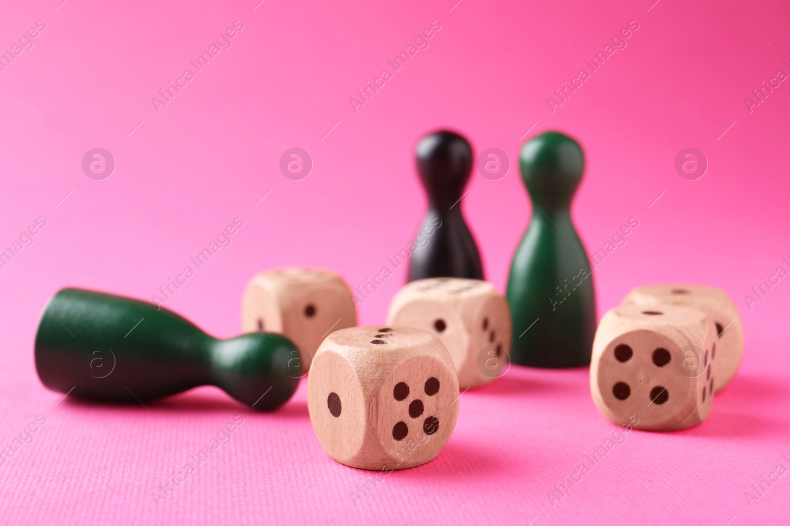 Photo of Wooden dices and color game pieces on pink background, closeup