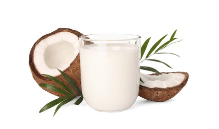 Glass of delicious vegan milk, coconut pieces and green leaves on white background