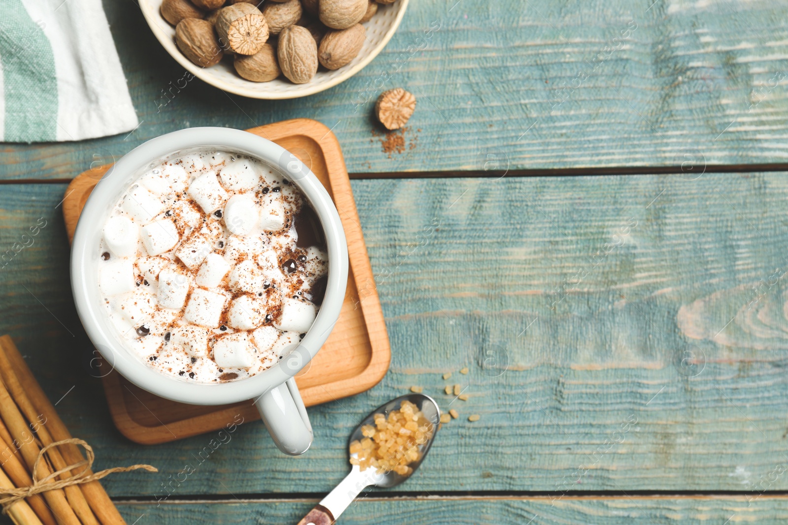 Photo of Hot drink with marshmallows and nutmeg powder on blue wooden table, flat lay. Space for text