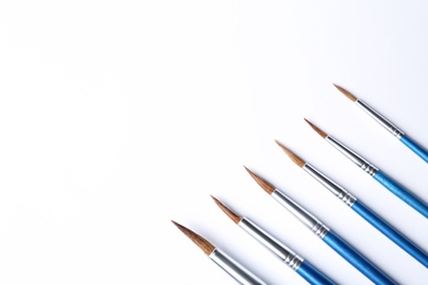 Photo of Different paint brushes on white background, top view. Space for text