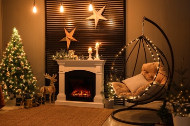 Beautiful living room interior with burning fireplace and hanging chair. Christmas celebration