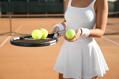 Photo of Sportswoman with racket and tennis balls at court, closeup