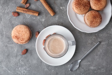 Photo of Glass cup with tasty hot cocoa drink and delicious macarons on table, top view