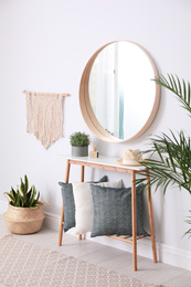 Photo of Round mirror and wooden table at home. Idea for interior design