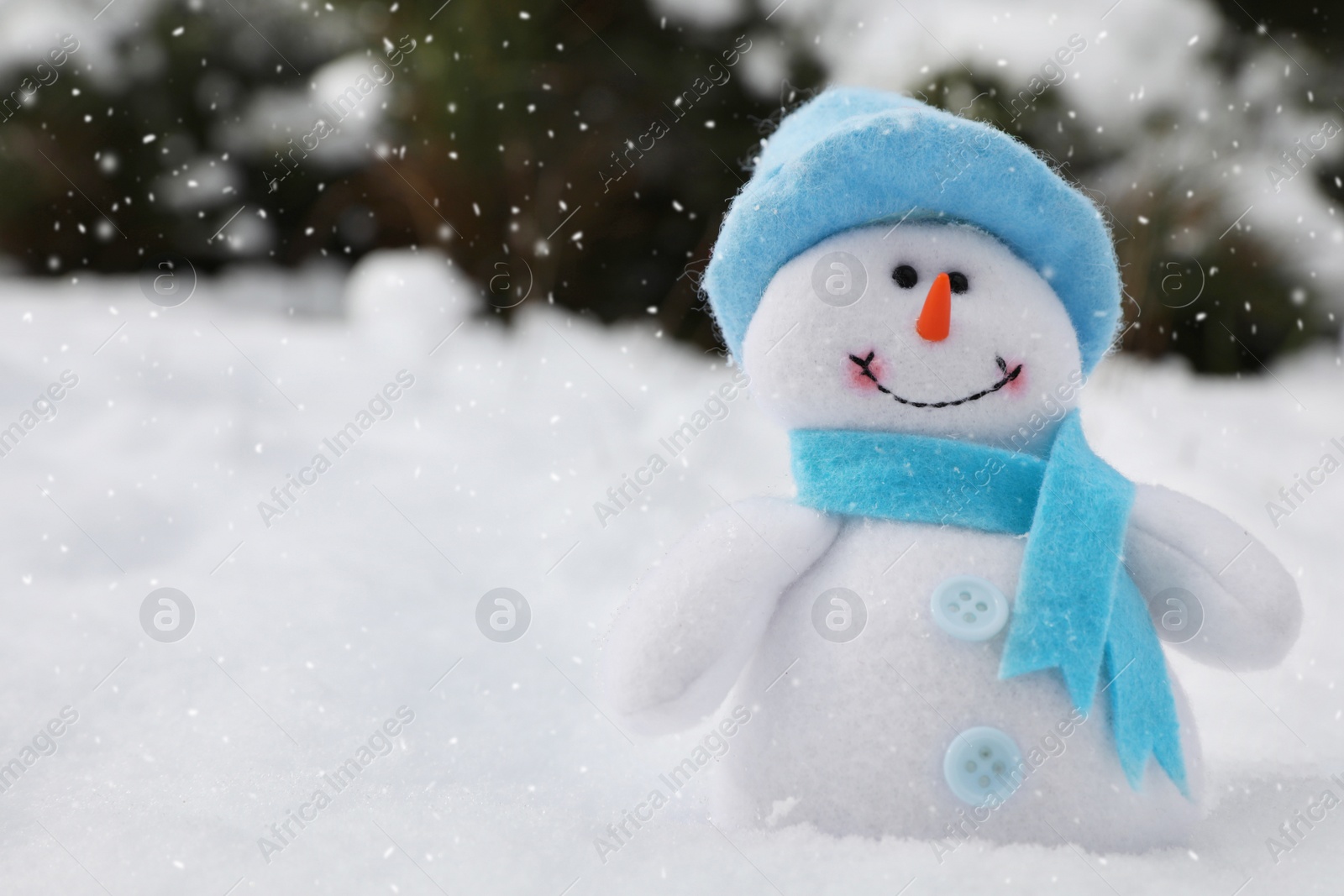 Photo of Cute small snowman toy on snow outdoors, space for text
