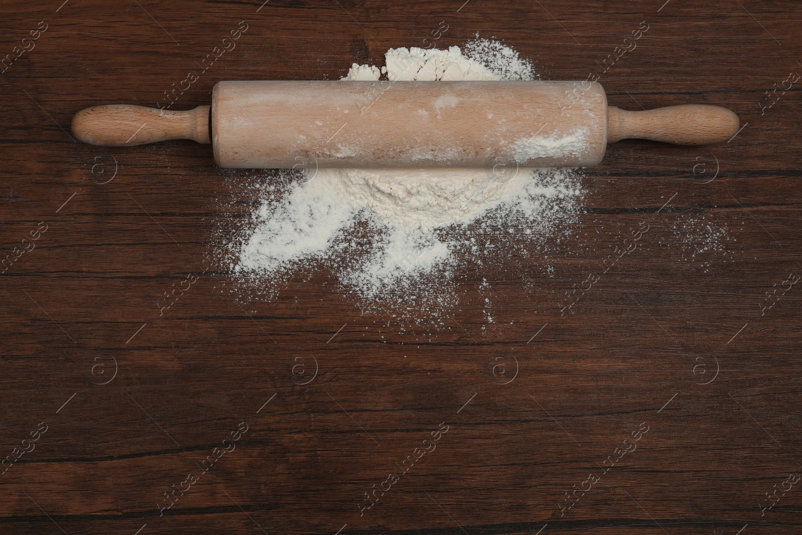 Photo of Flour and rolling pin on wooden table, top view. Space for text