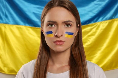 Photo of Young woman with face paint near Ukrainian flag