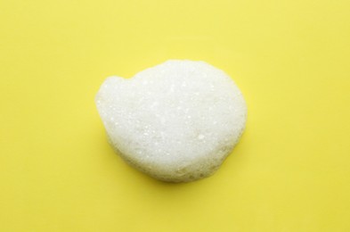 Photo of Drop of bath foam on yellow background, top view