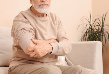 Senior man suffering from pain in his hand at home, closeup. Arthritis symptoms