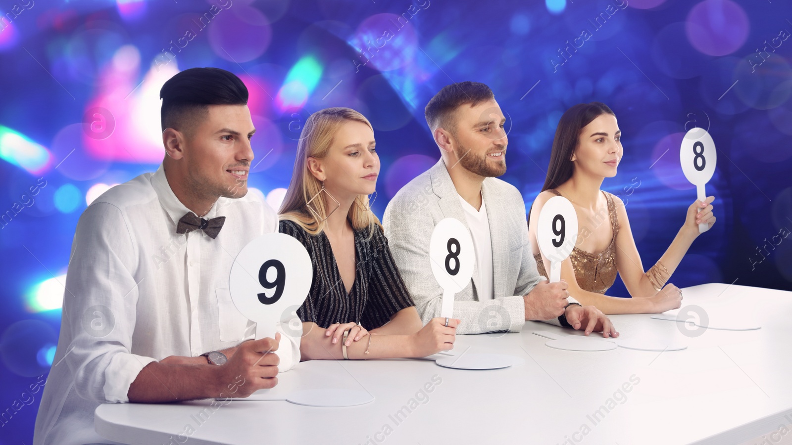 Image of Panel of judges holding different score signs at table against blurred background. Bokeh effect