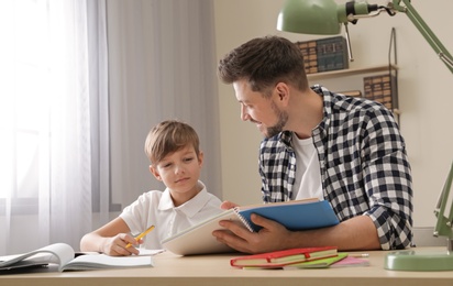 Photo of Dad helping his son with school assignment at home