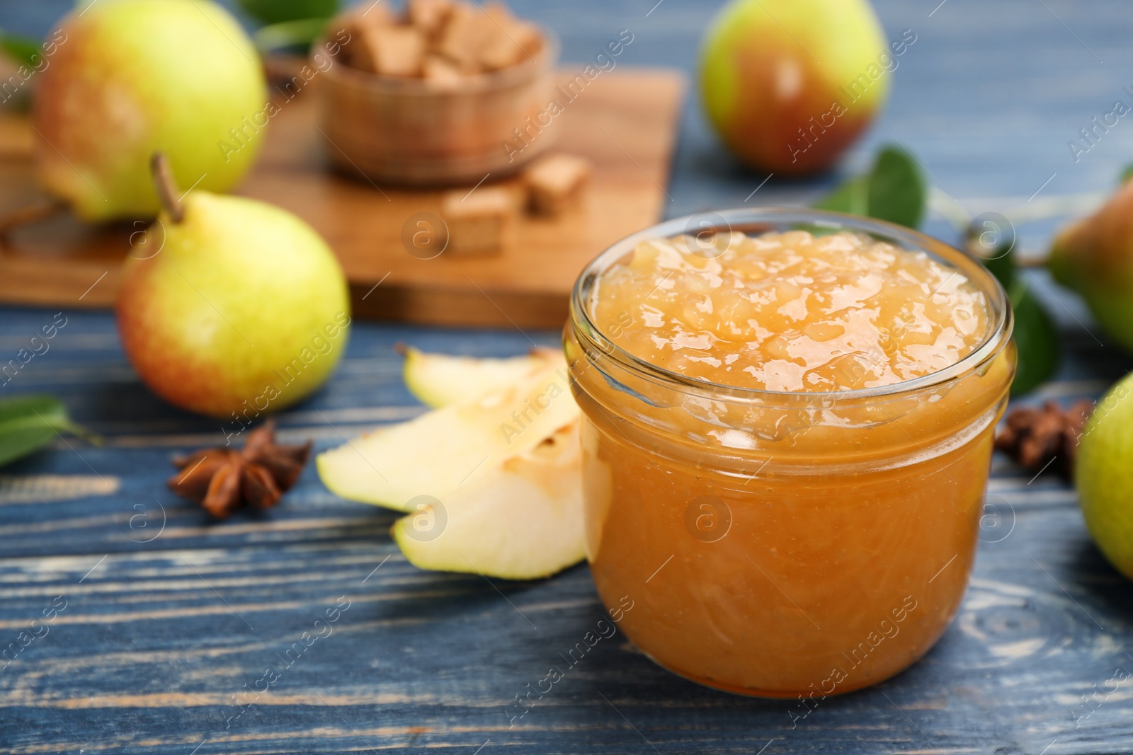 Photo of Tasty homemade pear jam and fresh fruits on blue wooden table