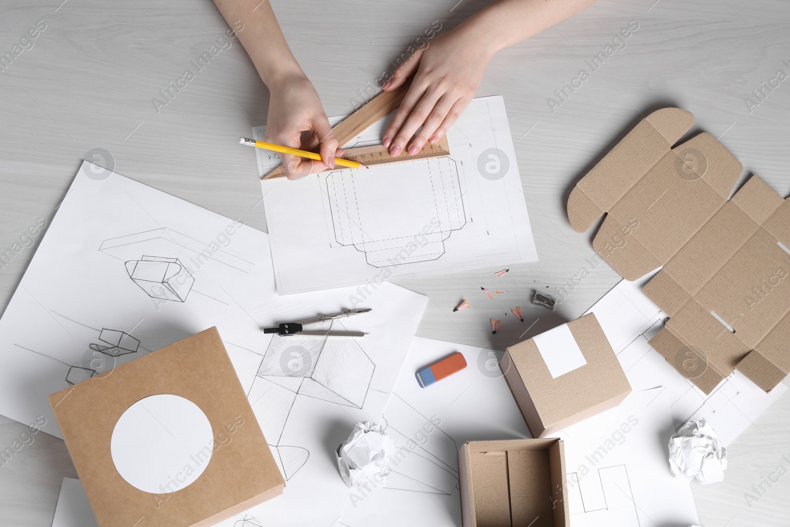 Photo of Woman creating packaging design at light wooden table, top view