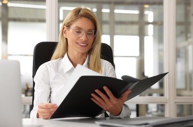 Smiling woman working at table in office. Lawyer, businesswoman, accountant or manager