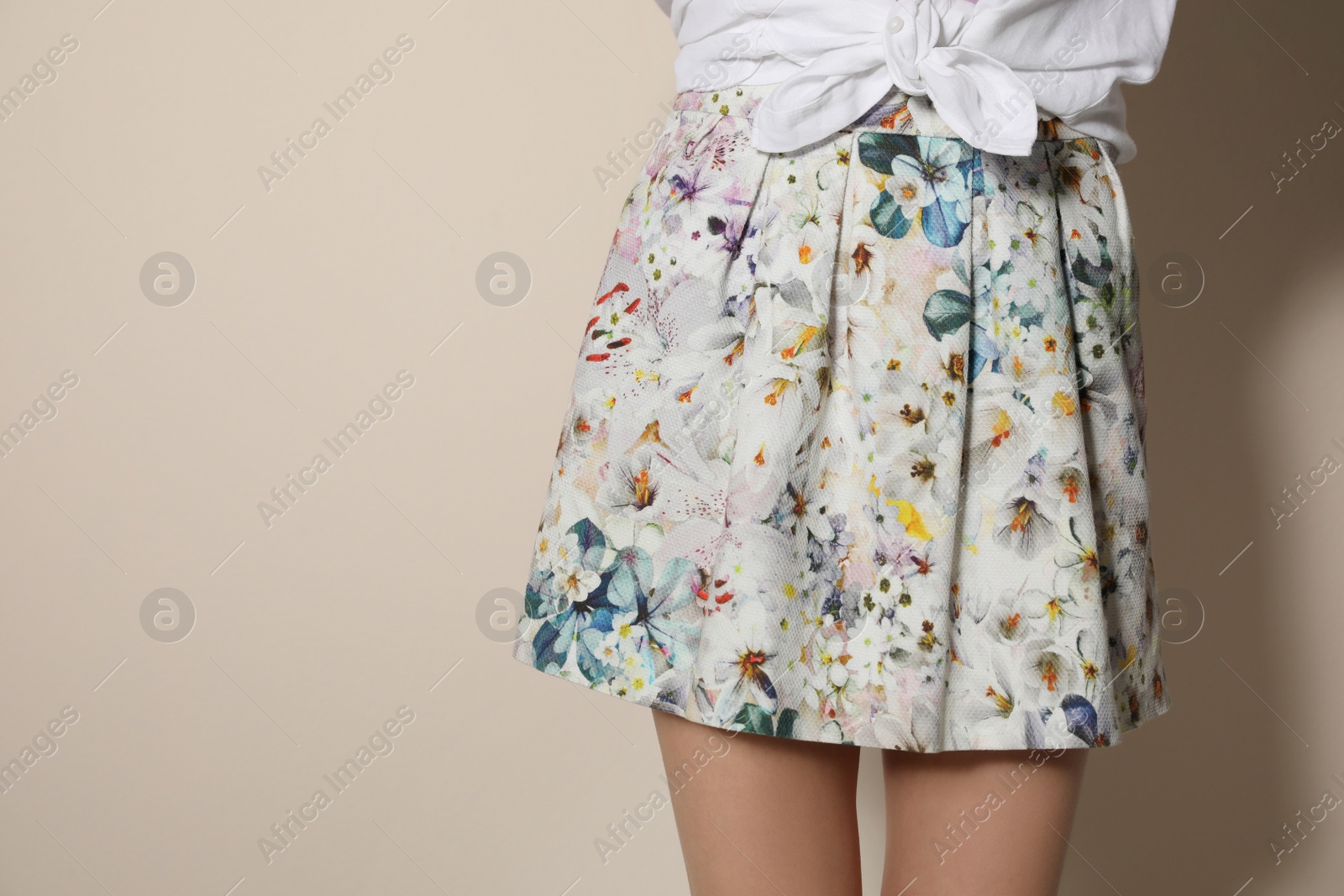 Photo of Young woman wearing floral print skirt on beige background, closeup