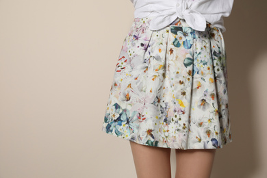 Photo of Young woman wearing floral print skirt on beige background, closeup