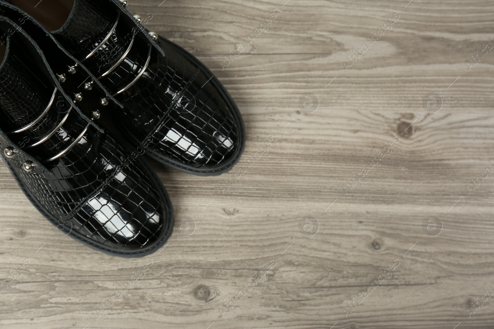 Photo of Pair of stylish ankle boots on wooden background, top view. Space for text