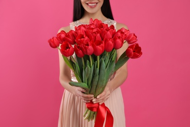 Photo of Happy woman with red tulip bouquet on pink background, closeup. 8th of March celebration