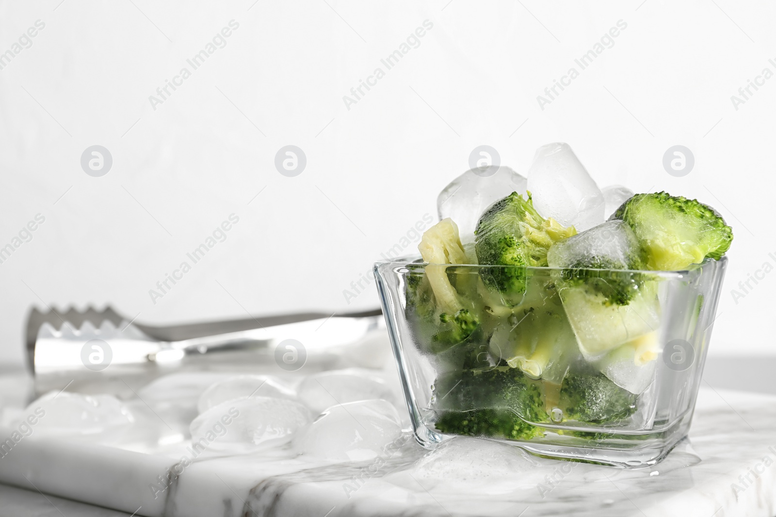 Photo of Bowl with frozen broccoli on marble board. Keeping vegetables fresh