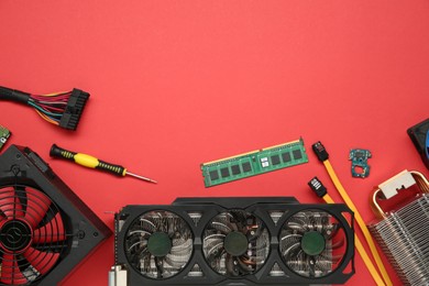 Graphics card and other computer hardware on red background, flat lay. Space for text