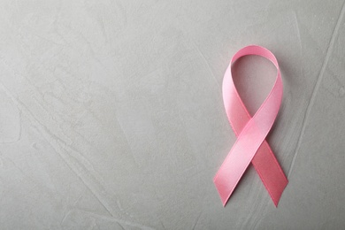 Pink ribbon on grey background, top view with space for text. Breast cancer awareness concept