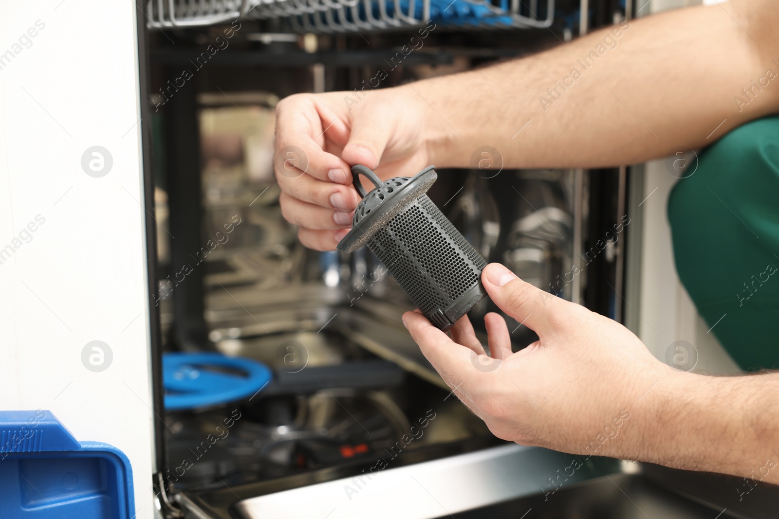 Photo of Repairman holding drain filter near dishwasher, closeup