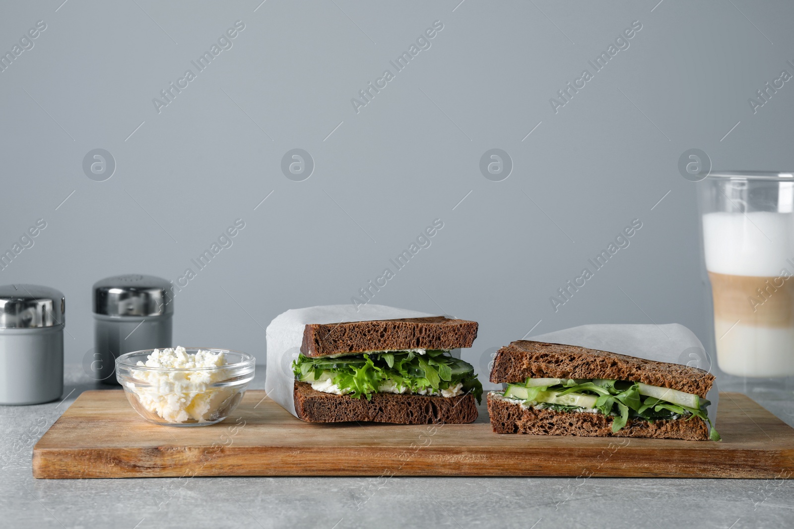 Photo of Tasty sandwiches with cream cheese, cucumber and greens on light grey table