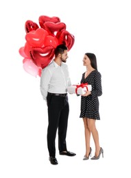 Happy young couple with heart shaped balloons and gift box isolated on white. Valentine's day celebration