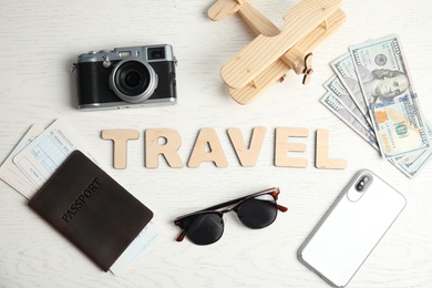 Flat lay composition with word TRAVEL, camera and passport on wooden background. Tourist agency