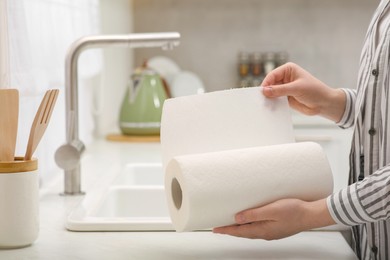 Photo of Woman tearing paper towels in kitchen, closeup