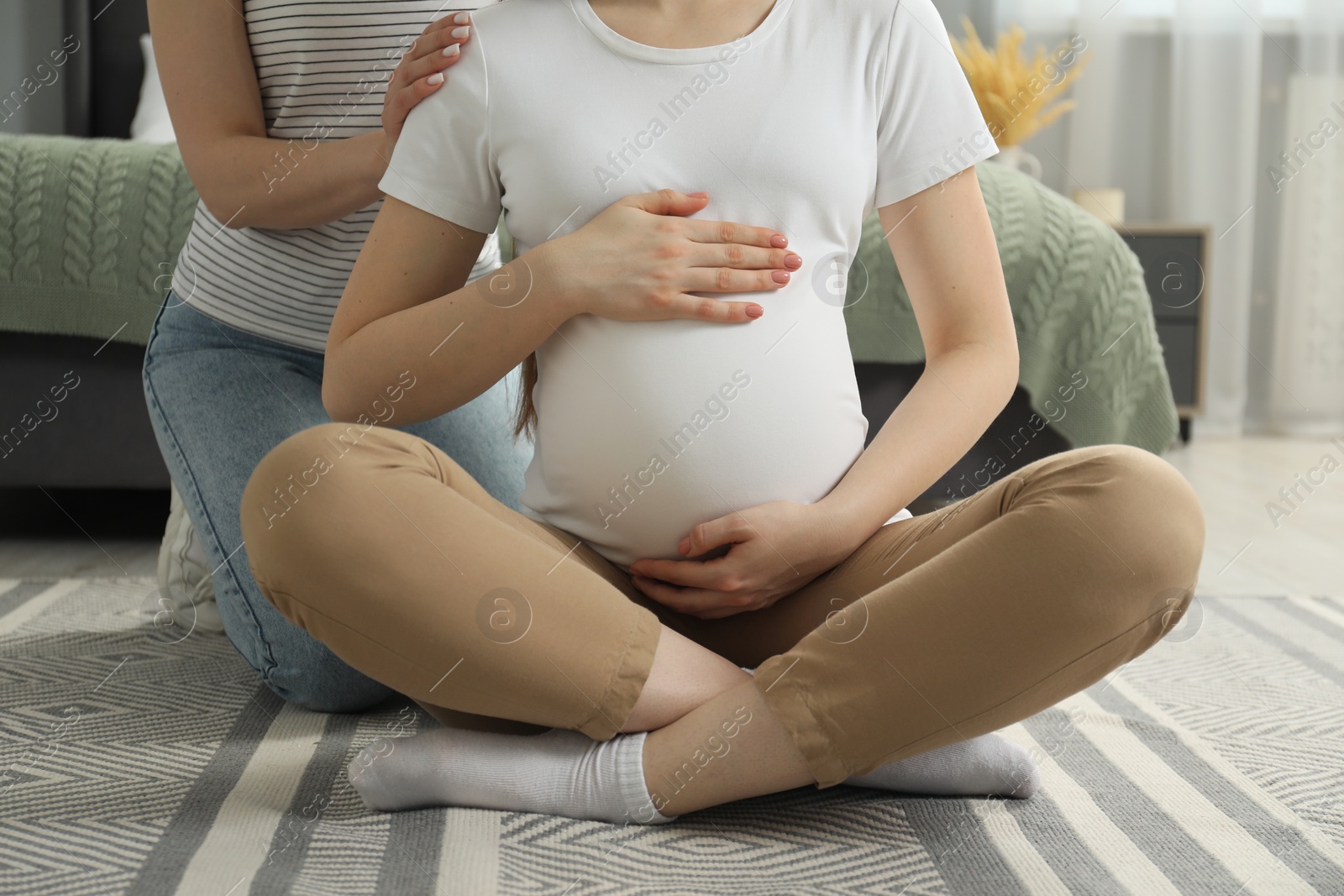 Photo of Doula taking care of pregnant woman indoors, closeup. Preparation for child birth