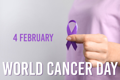 Image of Woman holding purple ribbon against grey background, closeup. World Cancer Day