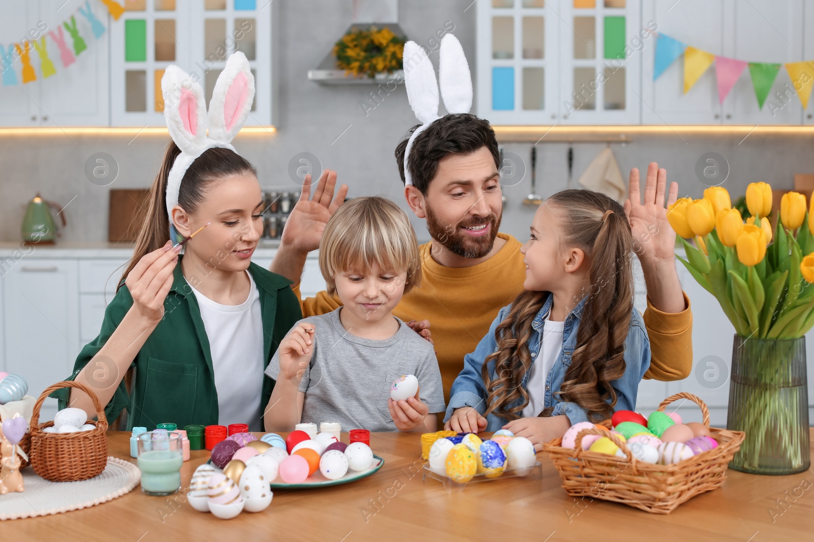 Photo of Happy family painting Easter eggs at table in kitchen