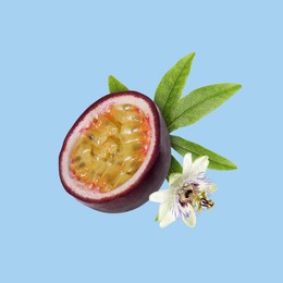 Half of passion fruit, leaf and passiflora flower falling on light blue background