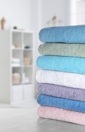 Image of Stack of fresh towels on light grey table in bathroom