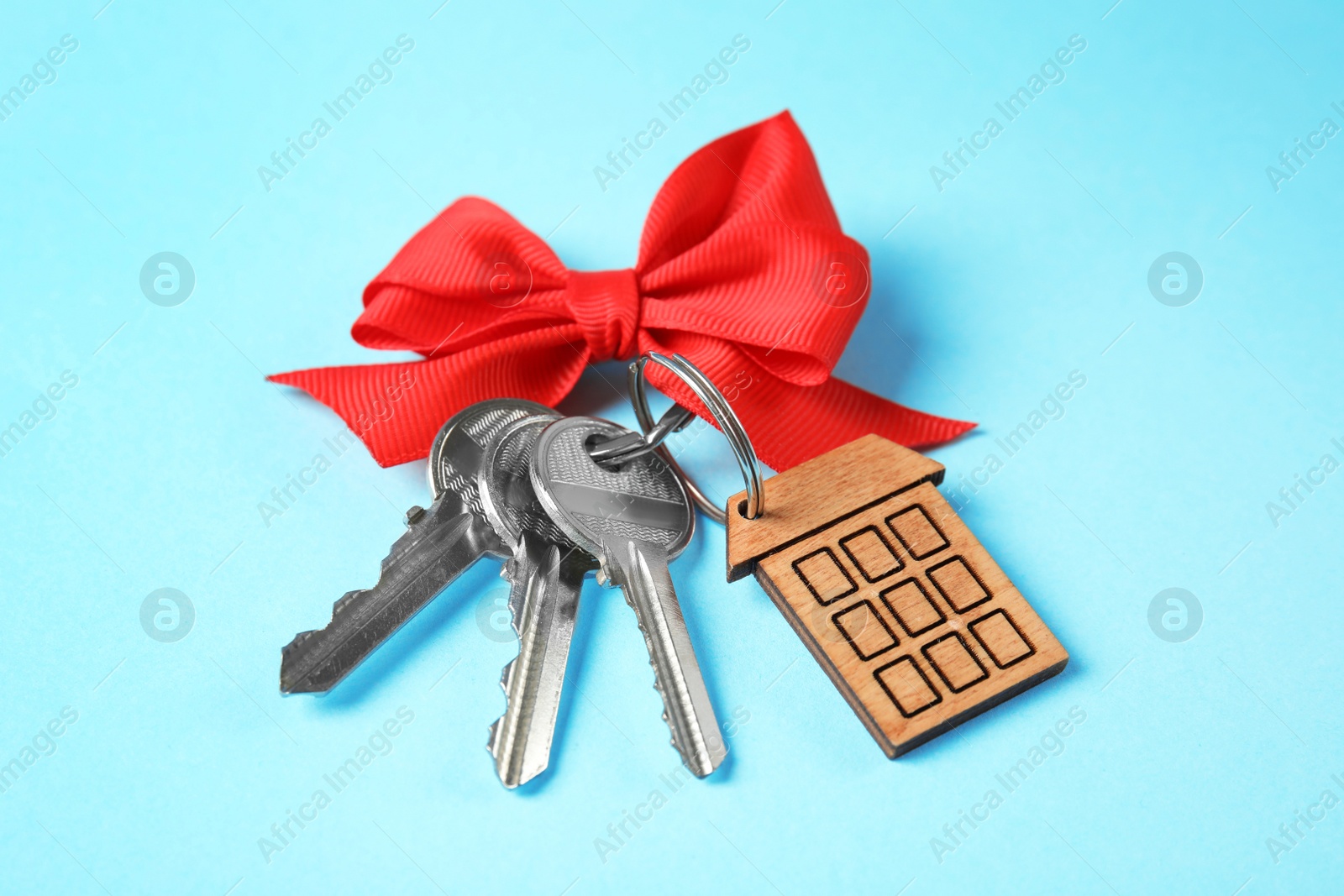 Photo of House keys with trinket and bow on color background