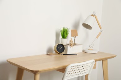 Photo of Comfortable workplace with wooden desk near white wall