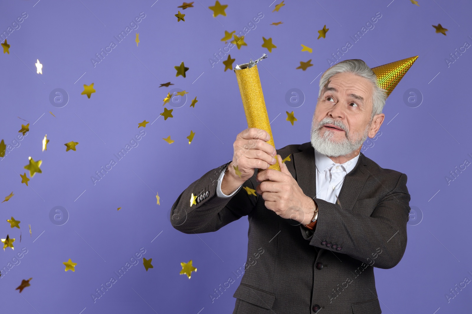 Photo of Man blowing up party popper on purple background